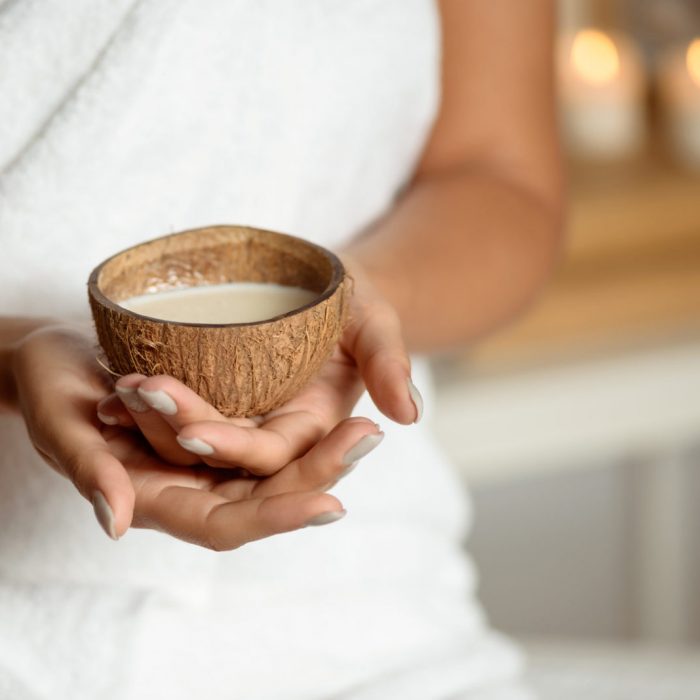 Close up photo of girl holding coconut in spa salon. Copy space.